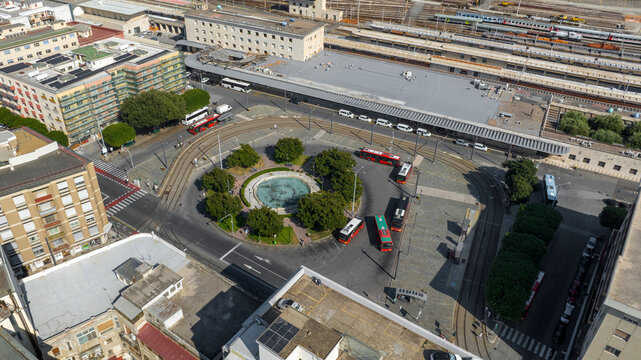 Aerial view of the Messina Centrale train station, located in Sicily, Italy. In the square in front of the station is the roundabout with the bus terminal. It is a sunny summer morning.