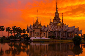 The beautiful golden buddhist temple with water reflect shadow in sunset time at Nakhon Ratchasima Thailand