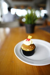 a cupcake on a white plate on a wooden table, breakfast menu in the morning, with natural lighting in the morning