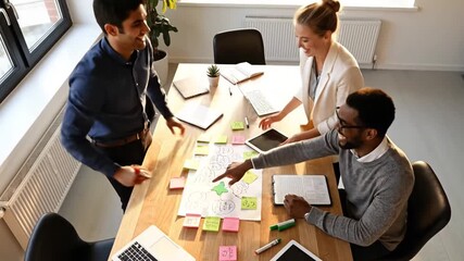 Diverse team collaborates on project strategy using sticky notes and tablets.