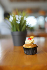 a cupcake on a white plate on a wooden table, breakfast menu in the morning, with natural lighting in the morning