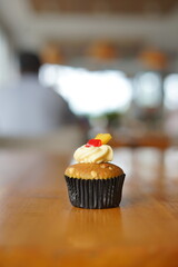 a cupcake on a white plate on a wooden table, breakfast menu in the morning, with natural lighting in the morning