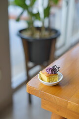 a cupcake on a white plate on a wooden table, breakfast menu in the morning, with natural lighting in the morning