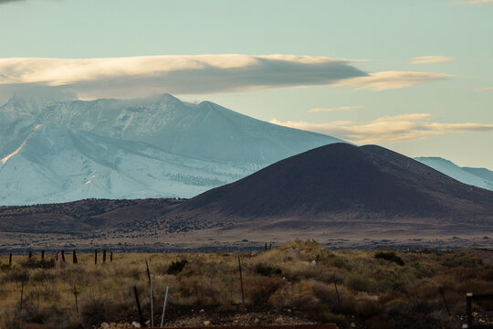 Dark hill against cloudy snowy mountain background