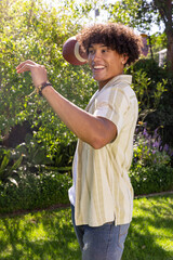 American football flying in sunny backyard garden with lush greenery and flowering plants