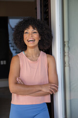 Fototapeta premium African american woman laughing while leaning against wooden door frame at home