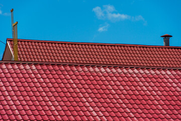 Naklejka premium A modern new building with a red tiled roof. Ventilation pipes protrude from the newly renovated roof. An office building for doing business.