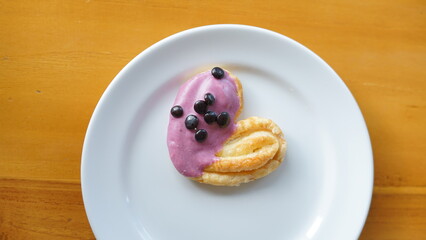 a cupcake on a white plate on a wooden table, breakfast menu in the morning, with natural lighting in the morning
