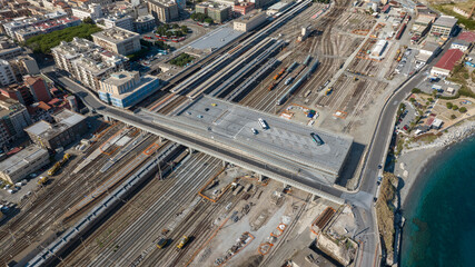 Aerial view of an urban overpass spanning a large railway yard. The infrastructure connects the city to the coast, highlighting complex transport logistics. It is Messina Train Station, Sicily, Italy.