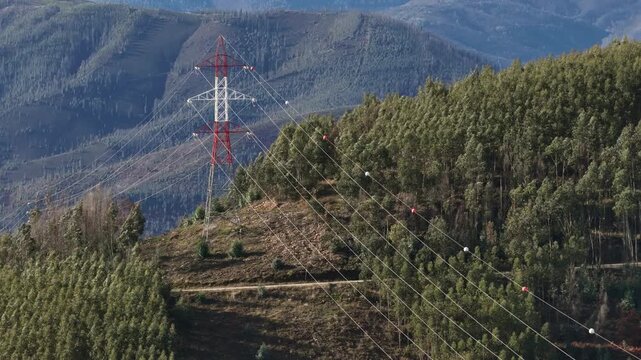Electric power lines and towers over mountains and forests zoom lens shot 2