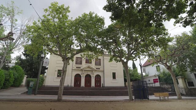 A wide view of the historic theater in La Garriga surrounded by lush trees.