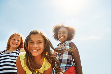 Fototapeta premium Outdoor, portrait and girls with smile for hang out, summer holiday and connection for bonding. Kids, weekend break and childhood friends with happiness for space, care and low angle for wellness