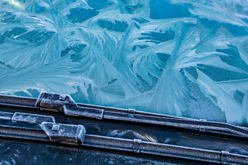 Frost forms on a car windshield during a cold morning in winter