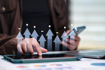 Professional trader analyzes financial growth statistics using digital tablet device. Rising arrow symbols represent corporate profit monitoring, market analysis, investment progress, economic