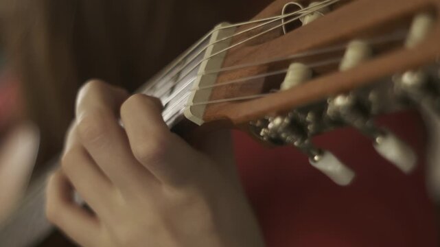 Cinematic close a teenager&rsquo;s hands playing a classical guitar, captured as one continuous visual scene focused on learning and musical development. The classical guitar&rsquo;s wooden body and nylon strings