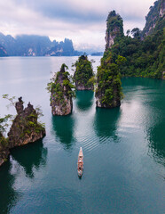 Naklejka premium Serene boat ride through the stunning landscape of Cheow Lan Lake in Khao Sok Thailand