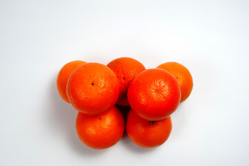 Ripe orange tangerines piled in a pile on a white background.