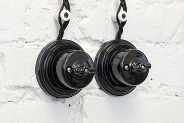 Vintage ceramic black light switch on the white brick wall. Switches in retro. 