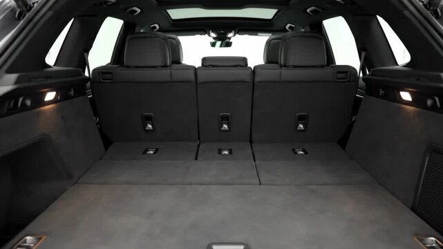 Car Trunk Space Interior - A view of the opened trunk of a car with lowered rear seats, offering a flat and spacious cargo area. The trunk is neatly organized and lined with soft gray carpeting.