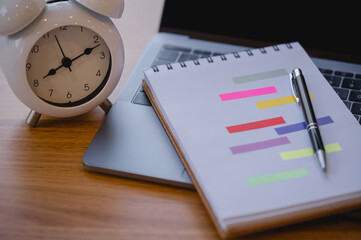 Computer laptop and calculator, alarm clock notebook with pen on wood table in appointment and...