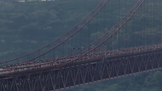 Runners participate in the Lisbon half marathon crossing the 25 de Abril Bridge over the Tagus River. Aerial drone footage