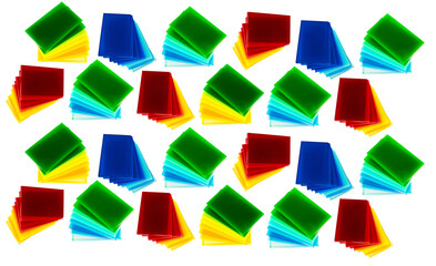 Scattered colored acrylic sheets form abstract pattern, Translucent plastic squares in bright red blue green yellow orange and black overlap on white surface