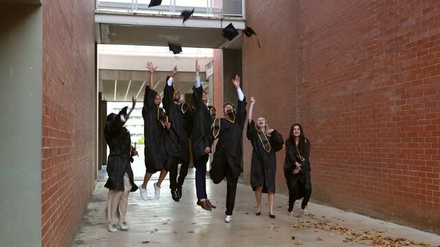 Group of diverse graduates celebrating by throwing caps in the air