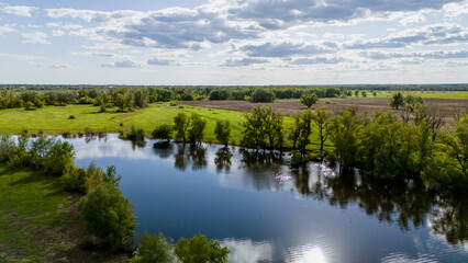 The Ural River, surrounded by green fields in spring, as seen from a drone