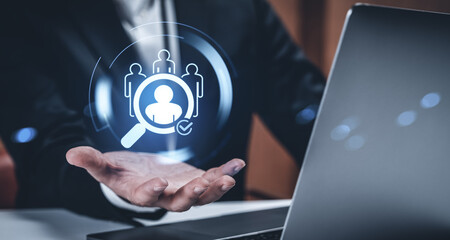 HR job search concept showing digital magnifying glass icon over candidate profile in businessman's...