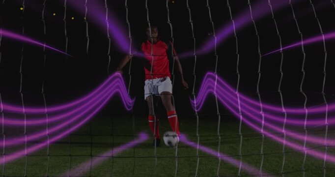 Animation of colorful light trails over african american male soccer player taking a penalty kick