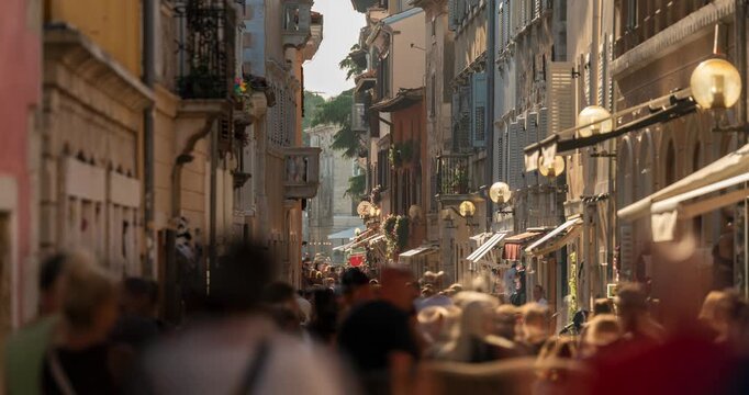 Porec, Croatia - August 13, 2025: Timelapse. Crowded narrow cobbled street in Porec old town filled with tourists during a sunny summer evening in Croatia