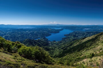 Fototapeta premium Aerial Vista of a Verdant Valley with Serene Lakes and Distant Cityscape under a Clear Blue Sky Offering an Escape into Nature's Beauty