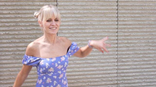 Joyful woman in floral dress, dancing happily outdoors with carefree expression