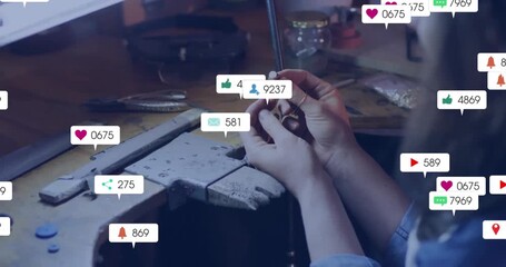 Jewelry craftswoman filing metal ring while notification icons growing around hands testing focus