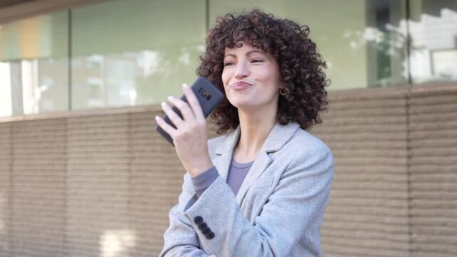 A young woman happily uses her smartphone outdoors in a busy urban area, showing modern trends