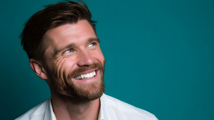 Fototapeta premium Man Smile Optimistically Against a Vibrant Teal Backdrop, Radiating Positivity and Hope, Making It Ideal for Motivational, Inspirational, and Lifestyle Content
