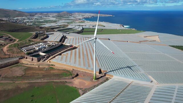 Aerial view of a wind turbine spinning near banana plantations on the coast of Gran Canaria