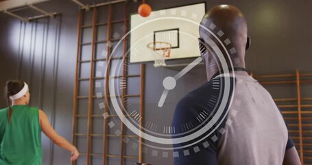 Coach timing with device, player releasing ball to hoop in gym, timer overlay tracking training