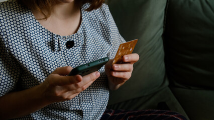 Online payment. Woman paying online using mobile phone and plastic bank card