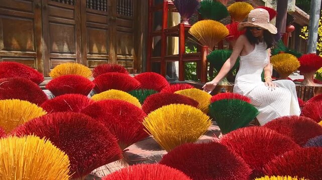 Tourist wear traditional vietnamese dress ao dai visit famous incense sticks village Quang Phu Cau pose surrounded by incenses in beautiful photographic location. Popular tourist travel destination