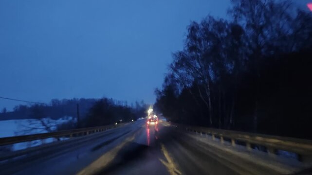 Driver point of view during driving in severe winter snowstorm with poor visibility, showing hazardous road conditions, limited traction, and challenging transport situation in extreme weather