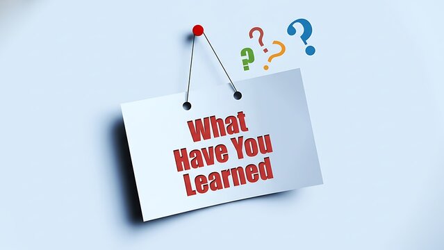 White paper pinned to light blue wall with red text 'What Have You Learned' and colorful question marks above - Powered by Adobe
