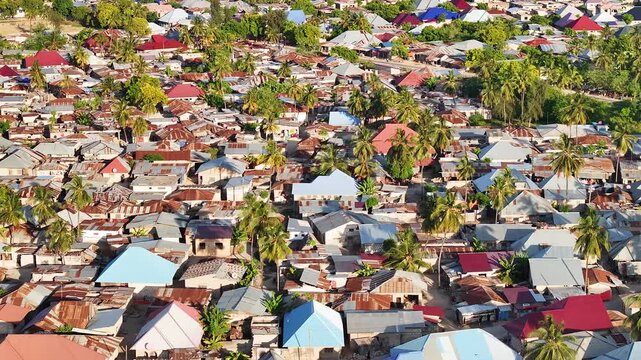 Cinematic drone 3x zoom shot flying above the rooftops of Nungwi, Zanzibar. Detailed view of coastal village life, tropical textures, and seaside atmosphere creates an immersive travel and culture sce