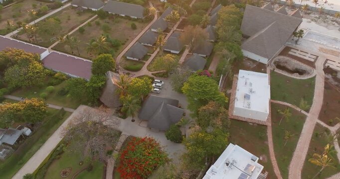 Cinematic forward-moving drone shot flying over a beach resort and revealing a breathtaking sunset at Nungwi Beach, Zanzibar. Golden sky, tropical coastline, and luxury atmosphere create a stunning tr