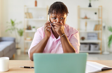 Scared african american woman at home talking on smartphone. Girl in office experiencing stress....