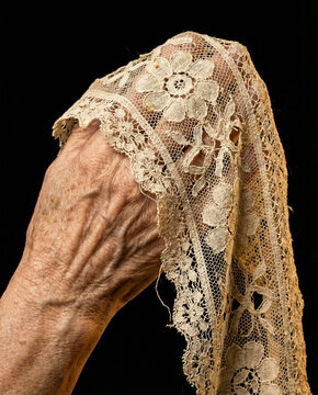 Encaje antiguo cayendo sobre la mano de una persona rezando