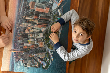 Two children, boys, assembling puzzleat home on a holiday day, playing together