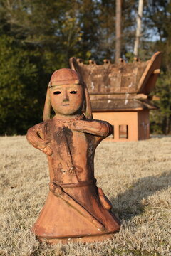 Ancient Japanese Yayoi period figure with traditional dwelling reconstruction