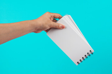A white notebook in hand against a blue background.