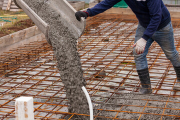 Closeup shot of concrete casting on reinforcing metal bars of floor in industrial construction site
